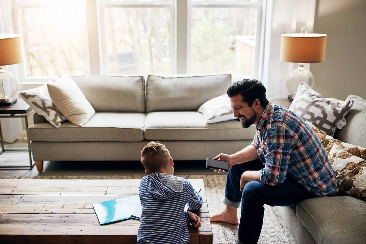 A father and his son relaxing in a bright, tidy living room
